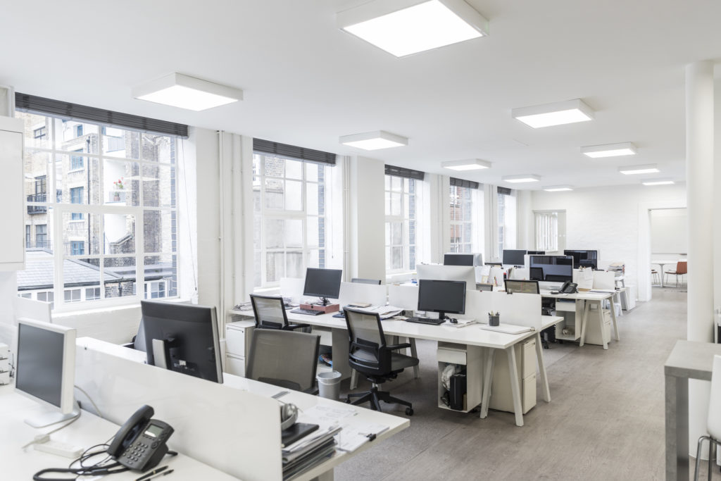 Large contemporary office environment with empty stations and electric ceiling lights